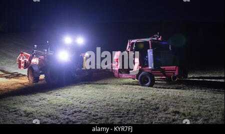 Farmer wrapping bales of silage at night in the dark. UK Stock Photo