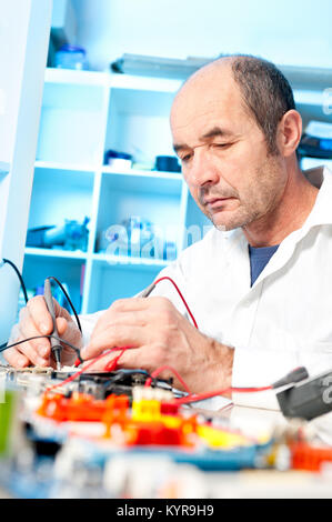 Senior male tech tests electronic equipment in service centre Stock Photo