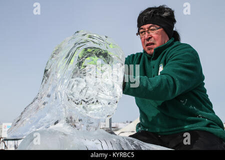 Inuit artist Bill Nasgaluak working on ice sculpture at the Long John Jamboree winter festival in Yellowknife, Northwest Territories, Canada. Stock Photo