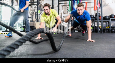 Men with battle rope in functional training fitness gym Stock Photo