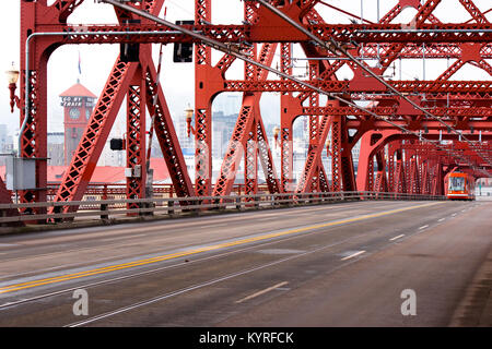 City tram going by the long lifting Broadway Bridge across the Willamette River in the center of Portland through the metal trusses Stock Photo