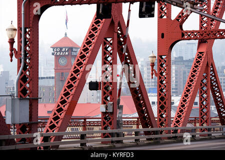 Red metal truss Broadway Bridge over Willamette River in the heart of Portland with a tower of the railway station on background Stock Photo