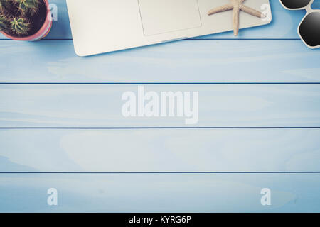 Laptop, sunglasses and cactus on blue wooden table Stock Photo