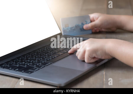 Kid Hands holding credit card and using laptop on white screen. Online shopping concept Stock Photo