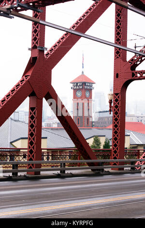 The Broadway Bridge across the Willamette River in the center of Portland through metal trusses of which one can see the tower of old train station Stock Photo