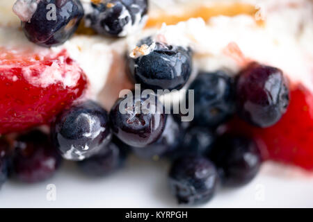 Appetizing fruit cake made of biscuit dough with a delicious sweet cream on which fresh strawberries and blueberries are laid melts Stock Photo