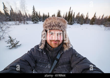 Close up portrait of middle aged man adventurer with frosted beard in forest or tundra during winter expedition Stock Photo