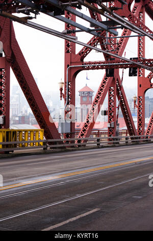 Lifting Broadway Bridge across the Willamette River in the center of Portland through the metal trusses of which one can see the tower of station Stock Photo