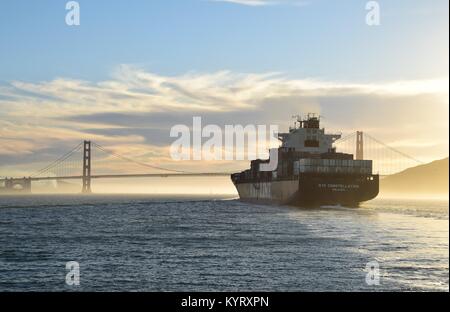 Container ship NYK Constellation leaves San Francisco Bay under the Golden Gate Bridge into the sunset.