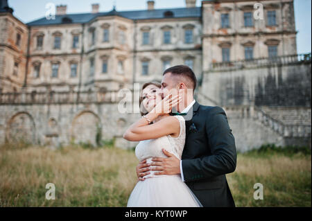 Fabulous wedding couple posing in front of an old medieval castle in the countryside on a sunny day. Stock Photo