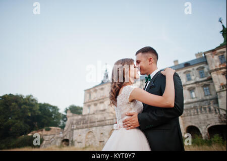 Fabulous wedding couple posing in front of an old medieval castle in the countryside on a sunny day. Stock Photo