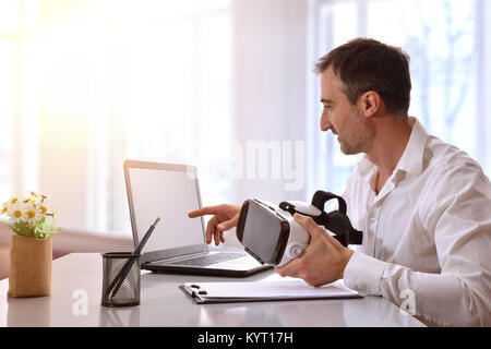 Office worker working with virtual reality glasses and computer in the office. Horizontal composition. Stock Photo