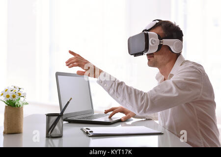 Office worker interacting with virtual reality glasses and computer in the office. Horizontal composition. Stock Photo