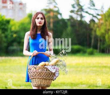 A beautiful girl with a basket in her hands and bread background Stock Photo