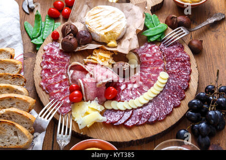 Delisious snacks on wooden board: sausages, bread, cheese, chestnuts and beer. Close view Stock Photo