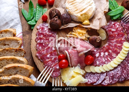 Delisious snacks on wooden board: sausages, bread, cheese, chestnuts and beer. Close view Stock Photo