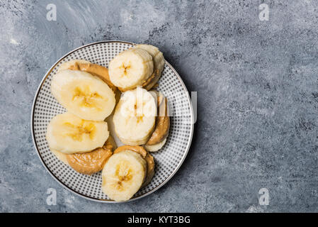 Light Healthy Snack made from Banana Slices and Cashew Butter on Grey Background Stock Photo