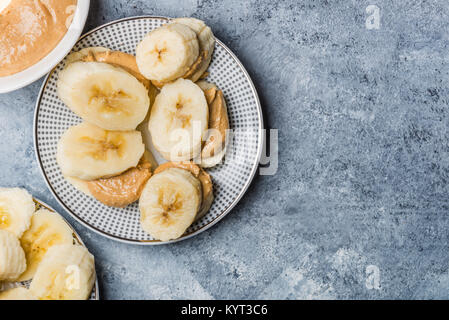 Light Healthy Snack made from Banana Slices and Cashew Butter on Grey Background Stock Photo