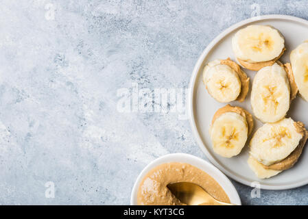 Light Healthy Snack made from Banana Slices and Cashew Butter on Grey Background Stock Photo