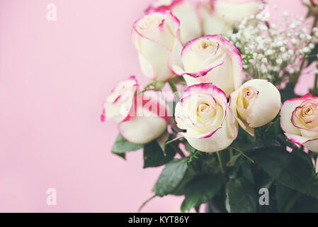Beautiful bouquet of  red and white roses with baby's breath against a pink background. Selective focus on roses in foreground with extreme shallow de Stock Photo