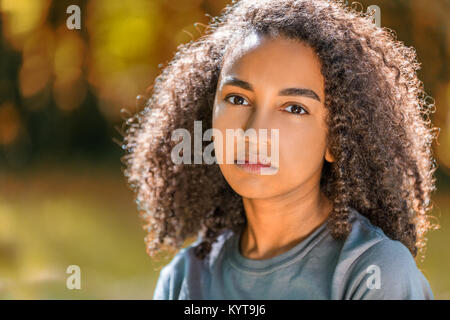 Beautiful mixed race African American girl teenager female young woman outside in autumn or fall looking sad depressed or thoughtful Stock Photo