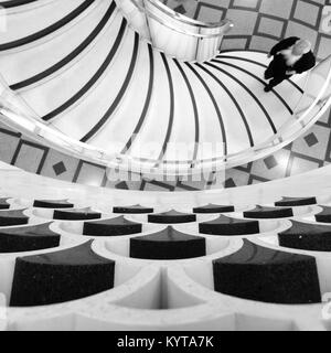 Detailed view of spiral staircase at Tate Britain art gallery in London UK with bearded man walking uo the stairs. Photographed in monochrome. Stock Photo