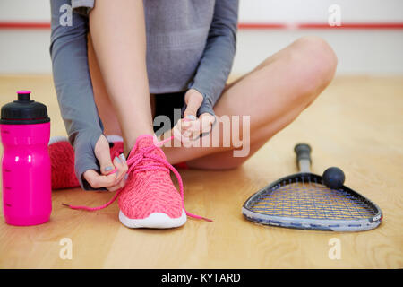 Unrecognizable woman tying sports shoe at court Stock Photo