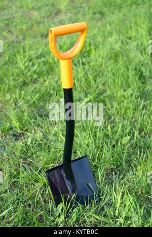 Shovel stuck in the grass lawn Stock Photo