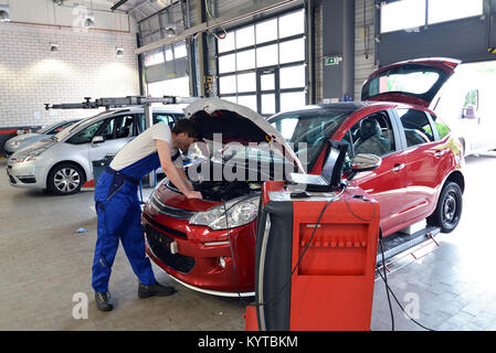 mechanic repairs motor from an automobile with the help of a diagnostic computer Stock Photo