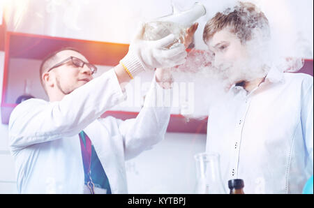 A bit of fume anyone. Curious schoolboy and a male chemistry teacher conducting an experiment in the school laboratory and having fun with a fume appe Stock Photo