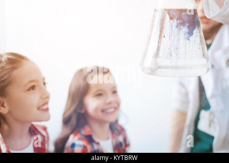 It is real magic. Scaled up shot of male scientist holding a flask with a liquid while little future chemists looking at the chemical reaction in the  Stock Photo