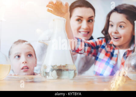 Creative chemistry. Future female scientists using a filter flask while participating in a chemical experiment held by a teacher wearing a laboratory  Stock Photo