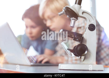 Enlarging things. Focused nice intelligent kid using computer for collecting needed data while working on their biology project in a lab Stock Photo