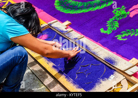Antigua, Guatemala - March 15, 2015: Woman makes Lent dyed sawdust procession carpet in town with most famous Holy Week celebrations in Latin America Stock Photo