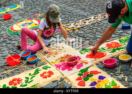 Antigua, Guatemala -  March 22, 2015: Locals decorate dyed sawdust Lent procession carpet in town with famous Holy Week celebrations Stock Photo