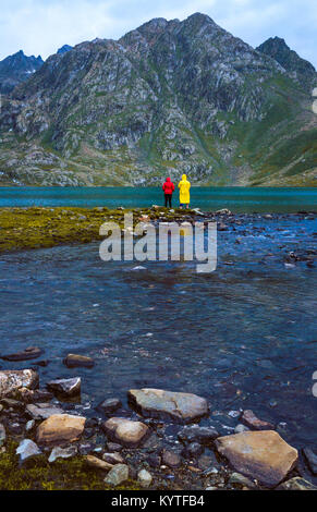 2 Friends fishing at Vishnusar lake on Kashmir great lakes trek in Sonamarg, India. Rocky terrain and  turquoise lake/tarn with snow mountains Stock Photo