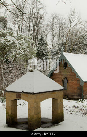 A snow covered mineral spring with the Old Magnesia Well Pump Room in the background Valley Gardens,Harrogate,North Yorkshire,England,UK. Stock Photo