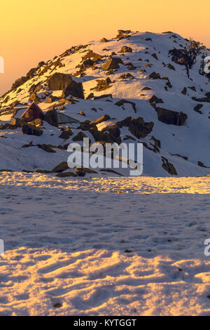 First rays of sun falling on a snow mountain called Triund in Mcleodganj,Dharamshala, Himachal pradesh, India at golden hour. Stock Photo