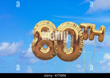 Gold number 80 foil birthday balloon against a bright blue summer sky. Golden party celebration. 3D Rendering Stock Photo
