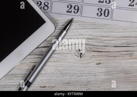 Tablet pc on wood table desk with calendar and pen Stock Photo