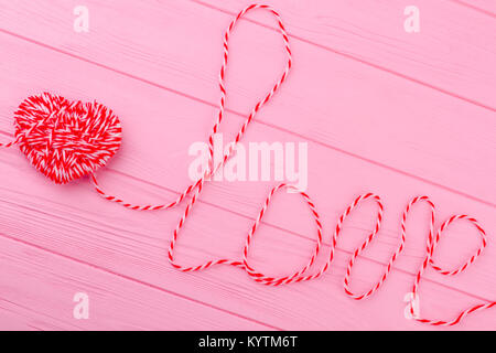 Letters love from thread, top view. Woolen heart on pink wooden background. Valentines Day design. Stock Photo