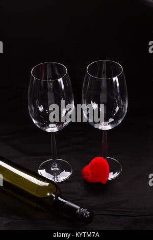 Two wine glasses and red heart. Bottle of wine and two blank wine glasses on black background. Red heart shaped jewel box. Happy Valentines Day. Stock Photo