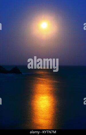 Moon and its reflection in the sea photographed from Lamorna Cove in Cornwall Stock Photo
