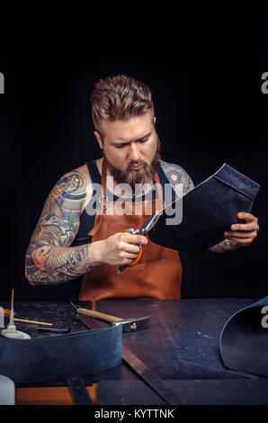 Leather Tanner working with leather using crafting tools in his shop Stock Photo