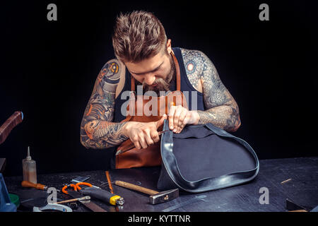 Leather Currier cutting leather outlines for his new production at his work area Stock Photo