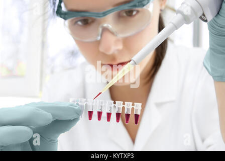 Young female scientist loads samples for DNA amplification by PCR into plastic tubes Stock Photo