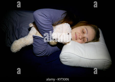 a young woman is sleeping on an orthopedic pillow with a soft indushka in a blue nightgown Stock Photo
