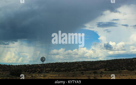 Dramatic sky with clouds and rain on the horizon over desert in Southwest US with windmill