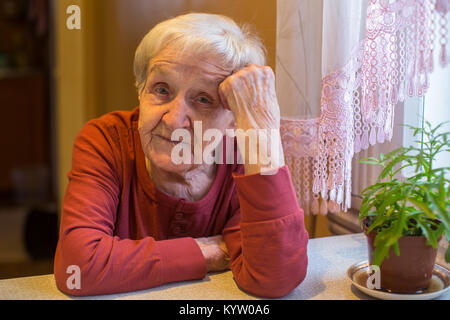 Elderly gray-haired woman, portrait sitting at the table. Stock Photo