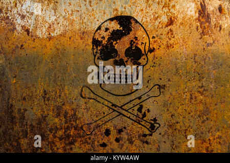 Skull and crossbones (symbolic for danger and life threatening) painted over a rusty metal plate texture background. Stock Photo